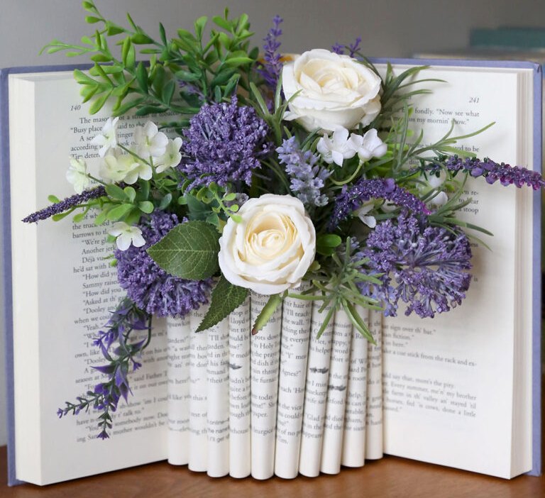 folded book vase holding purple and white flowers