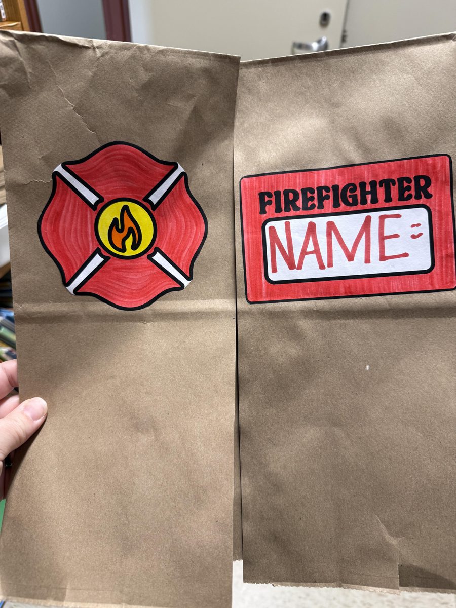 Paper bag firefighter jacket craft: a brown paper bag with a red firefighter badge on one side and a red Firefighter name tag on the other